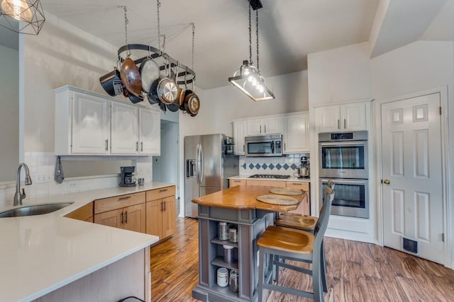 kitchen featuring white cabinets, sink, appliances with stainless steel finishes, tasteful backsplash, and decorative light fixtures