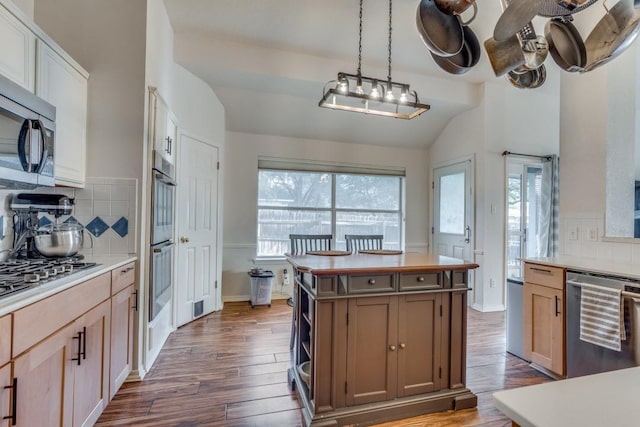 kitchen with pendant lighting, tasteful backsplash, stainless steel appliances, and lofted ceiling