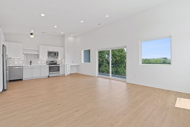 unfurnished living room with high vaulted ceiling and light hardwood / wood-style flooring