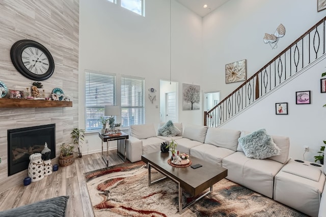 living room with hardwood / wood-style flooring, plenty of natural light, a towering ceiling, and a tile fireplace