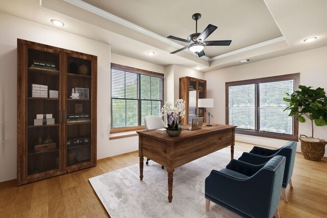 home office featuring visible vents, ceiling fan, light wood-type flooring, ornamental molding, and a raised ceiling