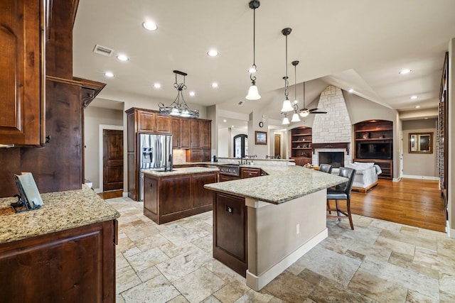 kitchen featuring stone tile floors, visible vents, a spacious island, open floor plan, and a large fireplace