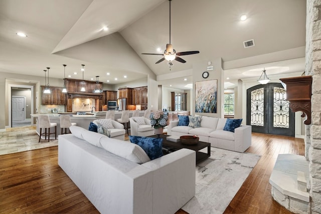 living room featuring visible vents, hardwood / wood-style floors, french doors, high vaulted ceiling, and a ceiling fan