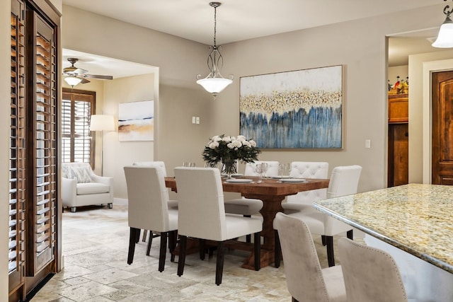 dining space featuring ceiling fan and stone tile flooring