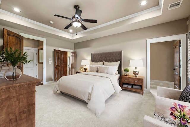 bedroom featuring light carpet, visible vents, crown molding, and a tray ceiling