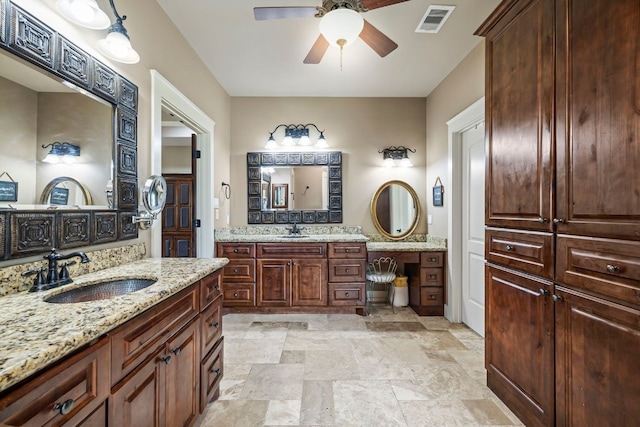 full bath with ceiling fan, stone finish floor, visible vents, and a sink