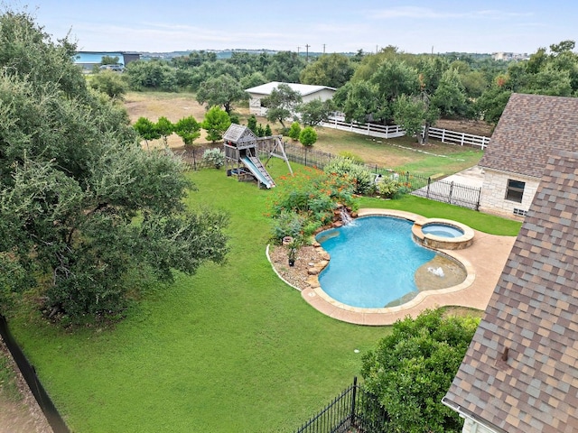 view of pool featuring a playground, a lawn, a fenced backyard, and a pool with connected hot tub