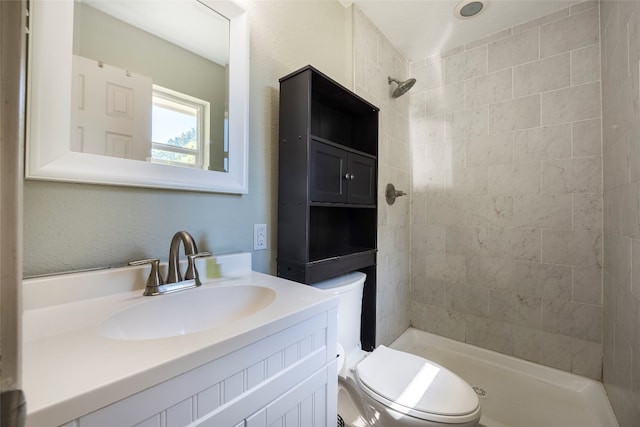 bathroom with vanity, a tile shower, and toilet