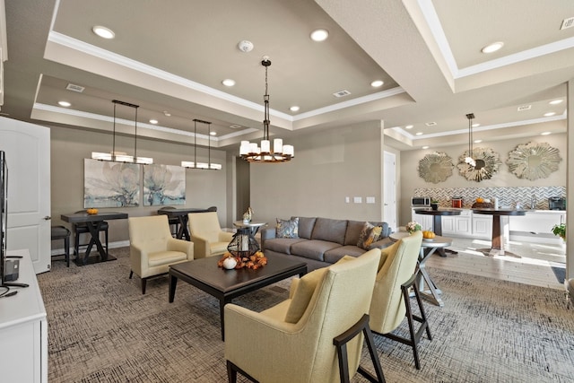 living room with ornamental molding, a tray ceiling, a chandelier, and hardwood / wood-style flooring