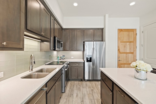 kitchen with light hardwood / wood-style floors, tasteful backsplash, dark brown cabinets, sink, and stainless steel appliances