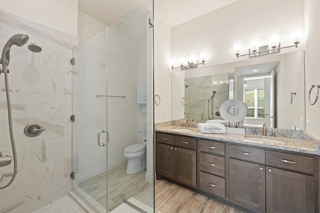 bathroom featuring hardwood / wood-style floors, toilet, walk in shower, and vanity