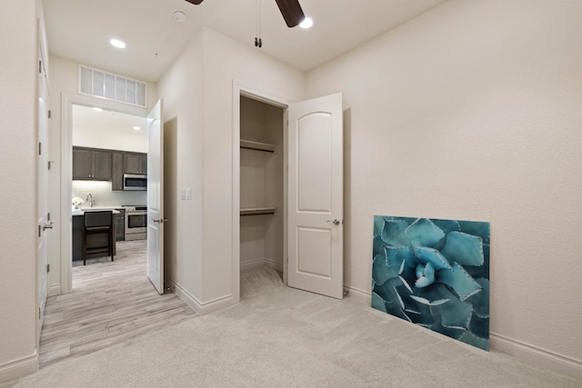 bedroom with a spacious closet, ceiling fan, a closet, light carpet, and sink