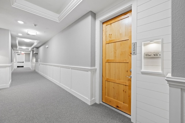 hallway with crown molding, carpet, and a raised ceiling