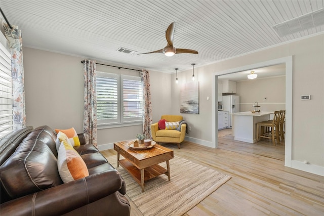 living room with light wood-type flooring, crown molding, and ceiling fan