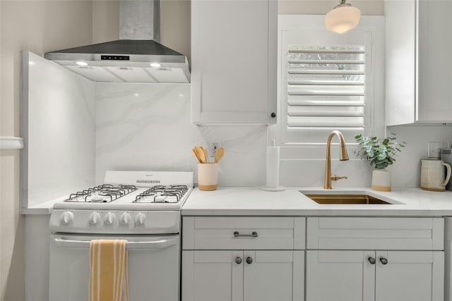 kitchen with white cabinetry, sink, wall chimney range hood, and white gas range oven