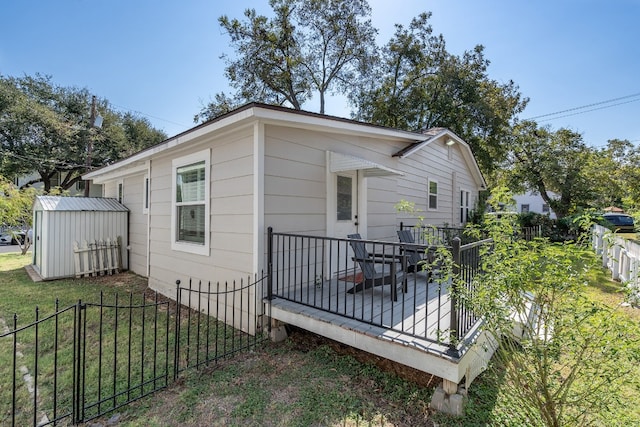 view of side of property with a deck, a lawn, and a storage unit