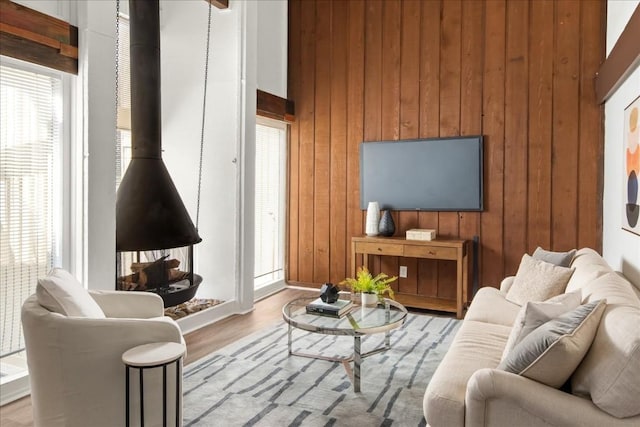 living room with wood walls, light hardwood / wood-style floors, and a towering ceiling