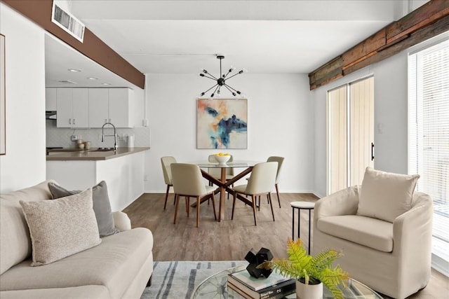 dining space featuring a notable chandelier, sink, and light hardwood / wood-style flooring