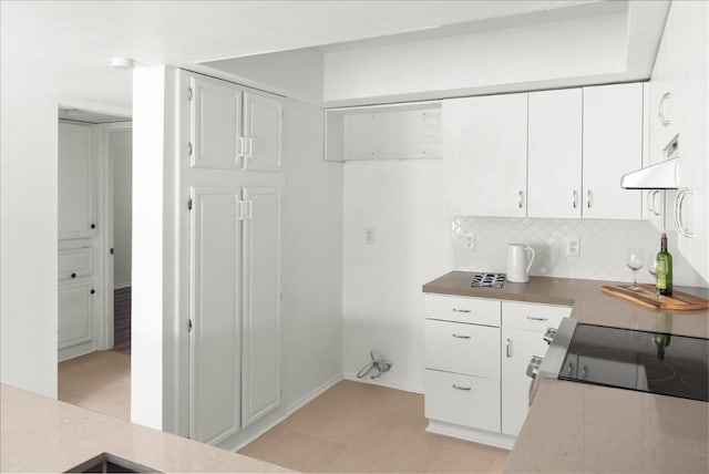 kitchen featuring white cabinets, decorative backsplash, and stove