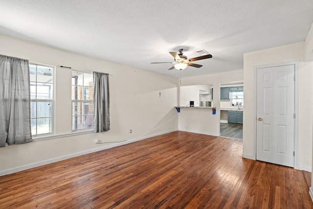 unfurnished living room with ceiling fan, dark hardwood / wood-style flooring, a textured ceiling, and sink