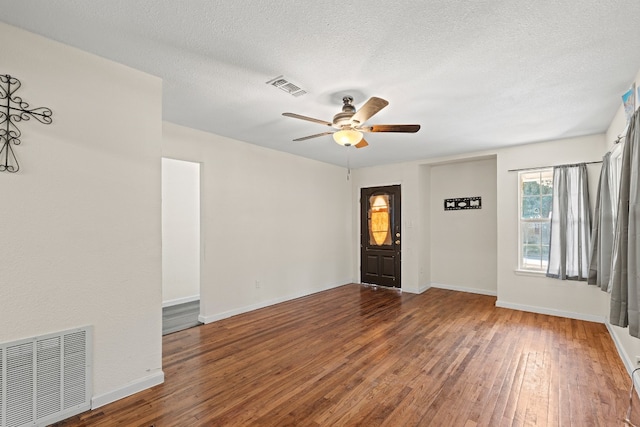 spare room with a textured ceiling, ceiling fan, and dark wood-type flooring