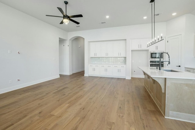 unfurnished living room featuring ceiling fan, sink, and light wood-type flooring