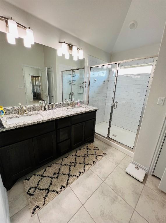 bathroom with lofted ceiling, vanity, a shower with shower door, and tile patterned floors