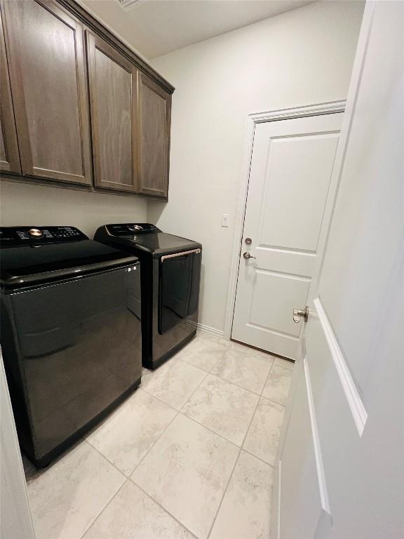 laundry area featuring cabinets, washing machine and dryer, and light tile patterned floors