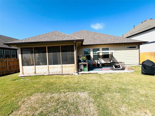 back of property with a fire pit, a sunroom, a yard, and a patio