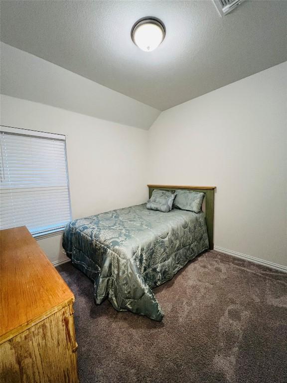 bedroom with lofted ceiling and dark carpet