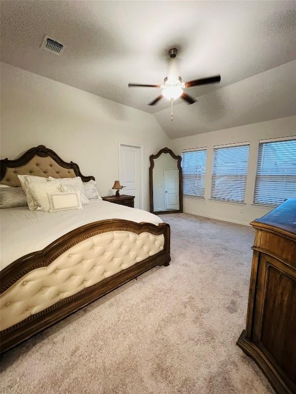 carpeted bedroom featuring ceiling fan, vaulted ceiling, and a textured ceiling