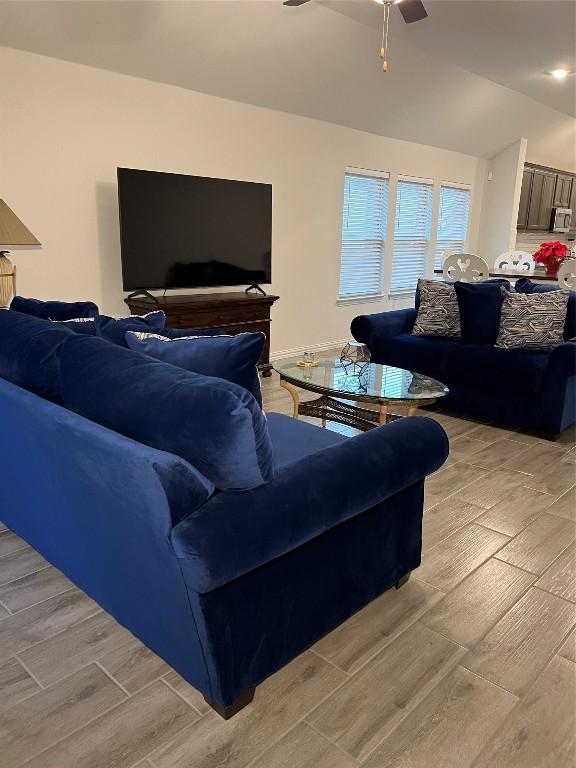 living room featuring ceiling fan and lofted ceiling