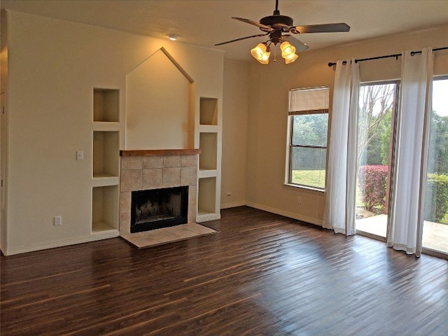 unfurnished living room with built in shelves, a fireplace, dark hardwood / wood-style flooring, and ceiling fan