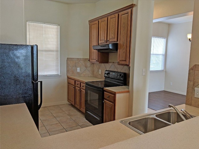 kitchen featuring black appliances, sink, light tile patterned floors, and tasteful backsplash