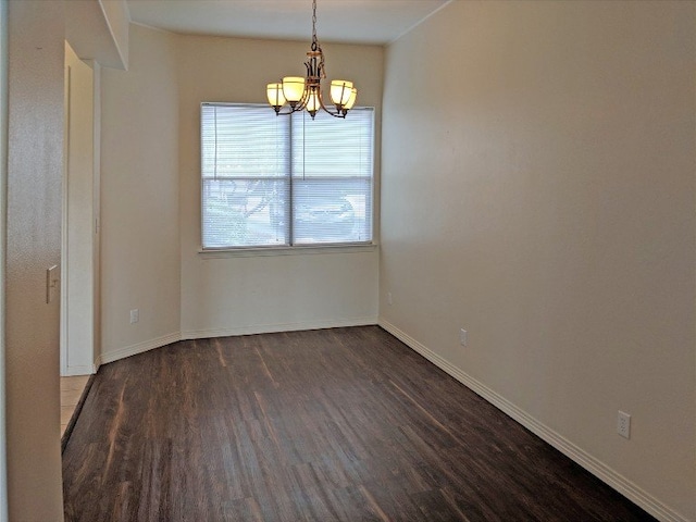 empty room with a chandelier and dark hardwood / wood-style flooring