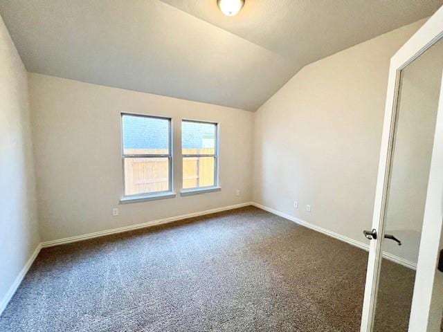 unfurnished room featuring dark carpet and lofted ceiling