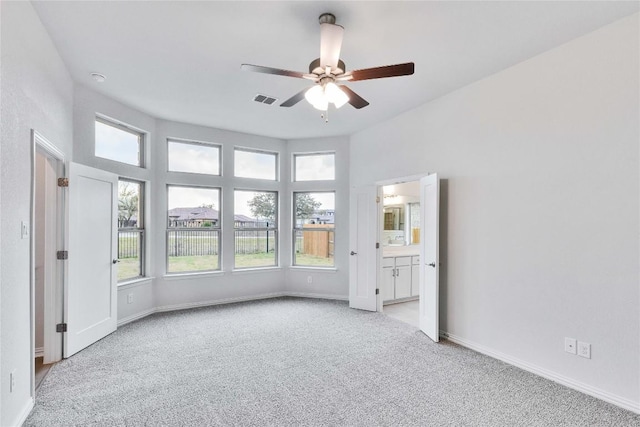 spare room featuring light colored carpet, a healthy amount of sunlight, visible vents, and baseboards