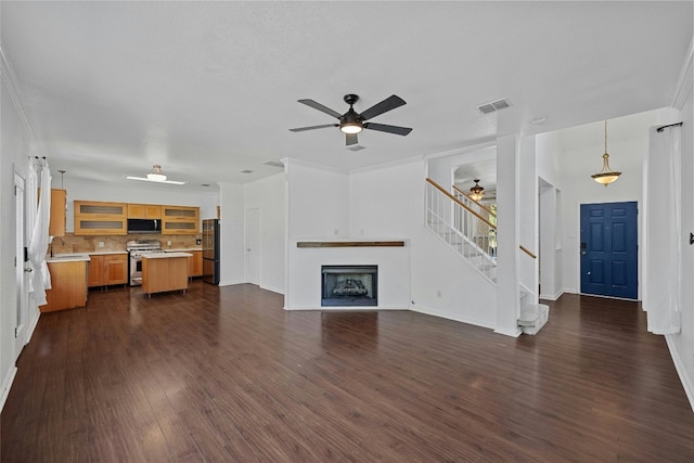 unfurnished living room with dark wood-type flooring, crown molding, sink, and ceiling fan