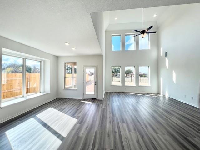 unfurnished living room featuring ceiling fan, plenty of natural light, dark hardwood / wood-style floors, and high vaulted ceiling