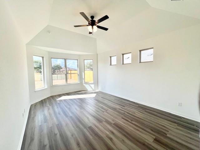 empty room with lofted ceiling, ceiling fan, and dark hardwood / wood-style floors