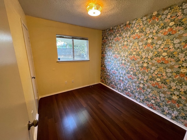 spare room featuring dark wood-type flooring and a textured ceiling