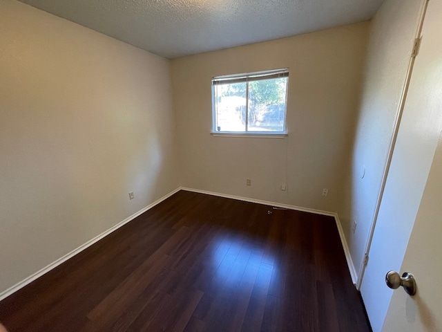 unfurnished room featuring dark hardwood / wood-style flooring and a textured ceiling