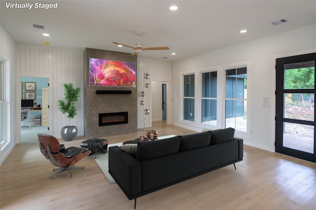 living room with ceiling fan, a fireplace, plenty of natural light, and light hardwood / wood-style flooring