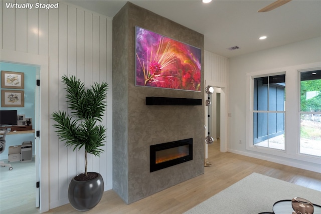 living room featuring a large fireplace, light hardwood / wood-style floors, and ceiling fan