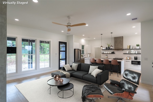 living room featuring sink, light hardwood / wood-style flooring, and ceiling fan