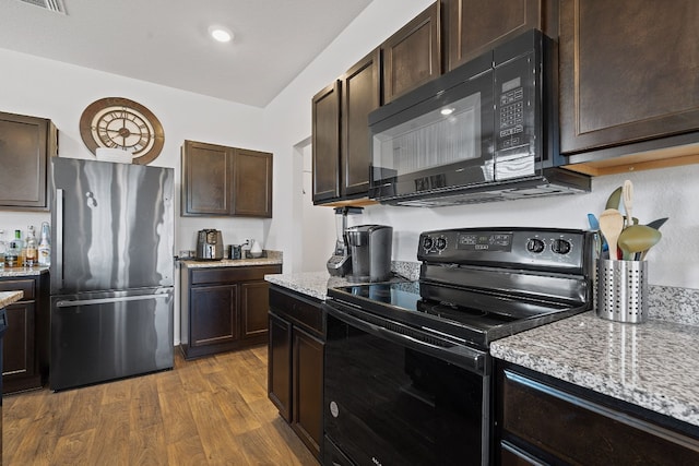 kitchen featuring dark wood-type flooring, black appliances, light stone counters, and dark brown cabinetry