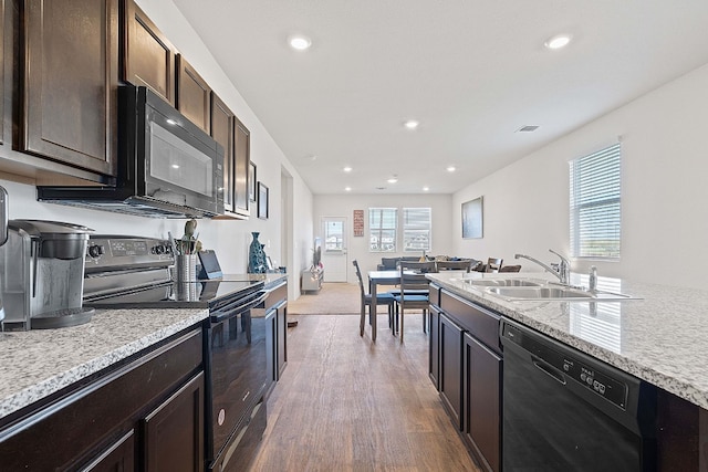 kitchen with dark brown cabinets, sink, light stone counters, dark hardwood / wood-style floors, and black appliances