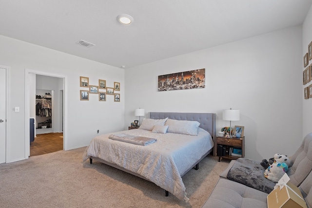 carpeted bedroom with a walk in closet