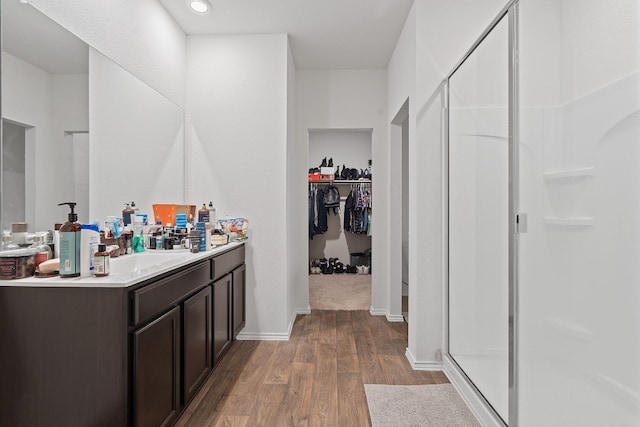 bathroom featuring a shower with door, vanity, and wood-type flooring