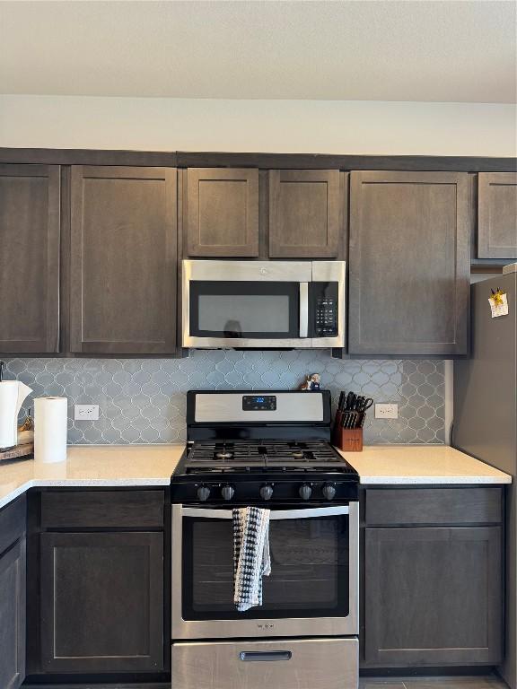 kitchen with stainless steel appliances, tasteful backsplash, and dark brown cabinets